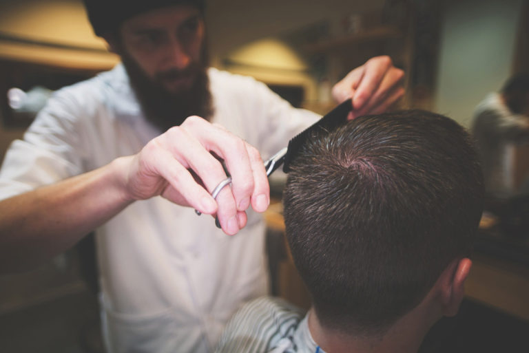 Barber giving customer scissor hair cut