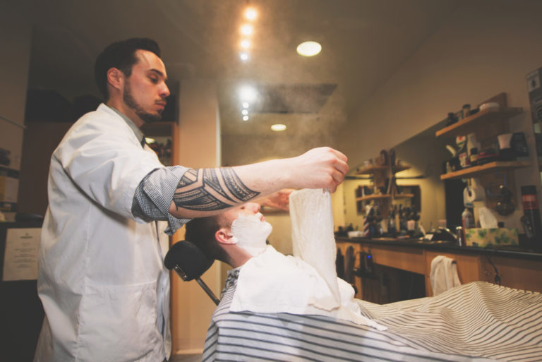 Barber giving customer hot towel shave steam lather